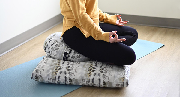 Yoga mat and cushion arranged on a floor ready for a gentle morning practice